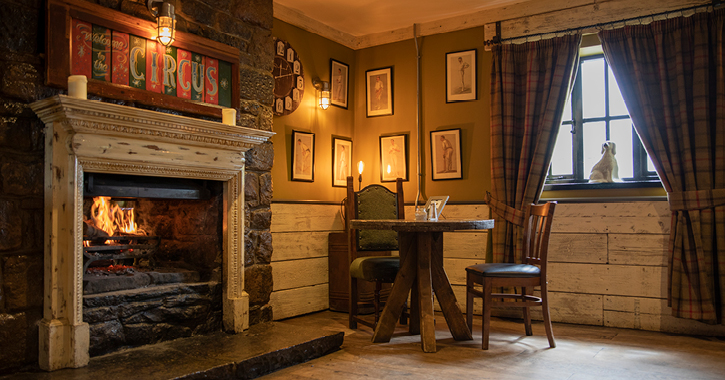 table and chairs next to open fire inside The South Causey Inn 